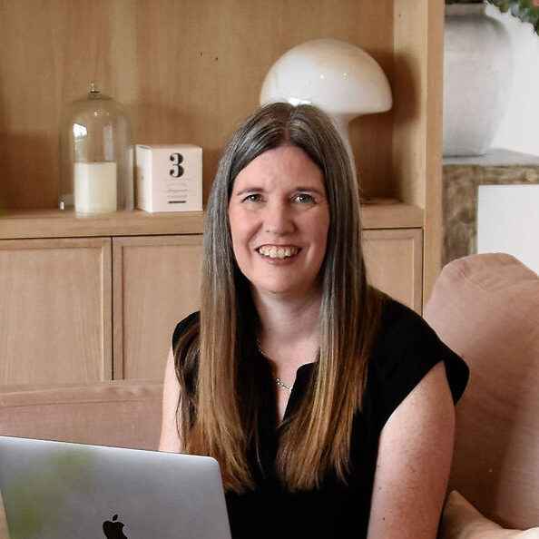 Image shows Helen, of Everything Crafty, sitting on the sofa with her laptop 